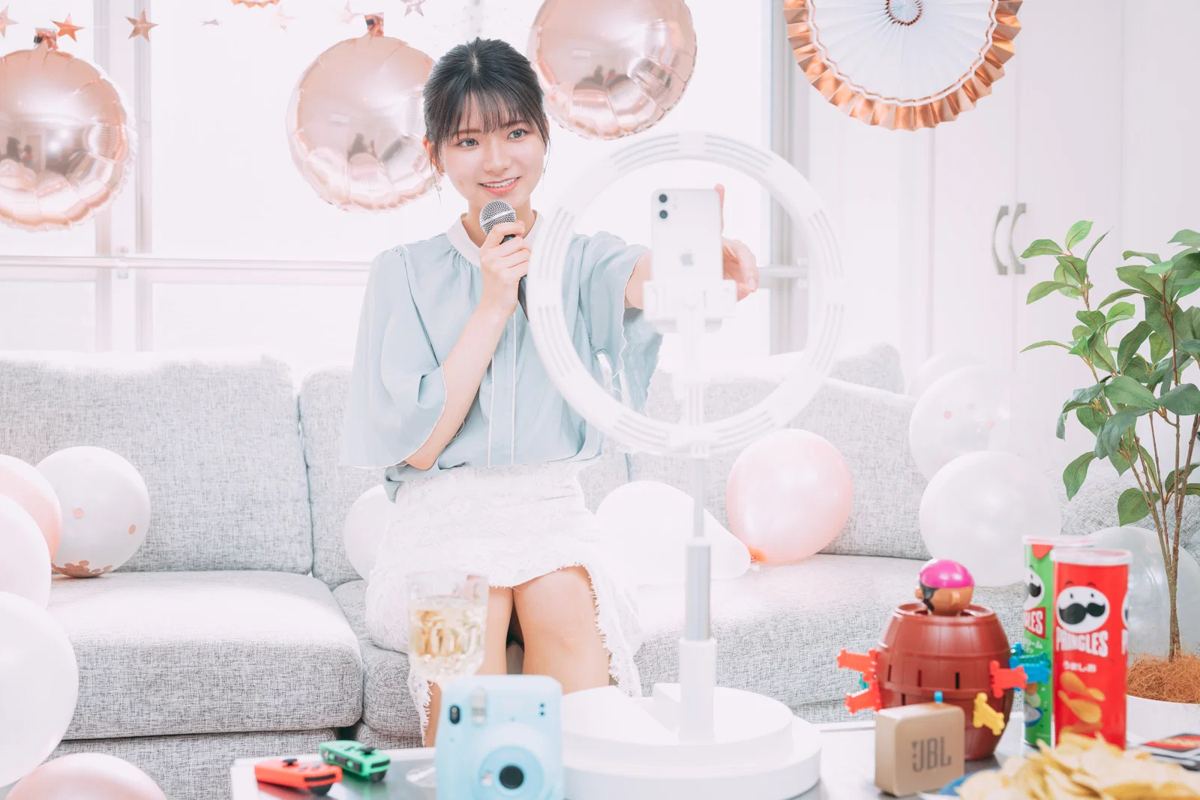 リングライトにスマートフォンを付けて配信する女性